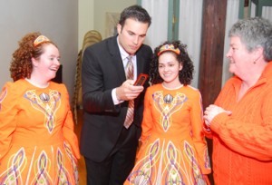 CBS 3's meteorologist Doug Kammerer checks out a cellphone picture with award-winning Rince Ri dancers Katie McGlynn and Marielle Baird.