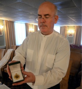 Father Ed Brady displays the H-Block memorial medal.